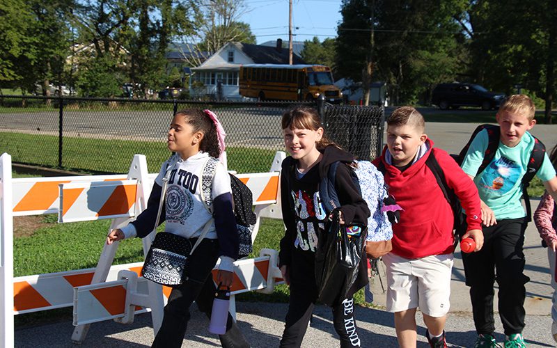 A group of four elementary students walk in a line after getting off a bus