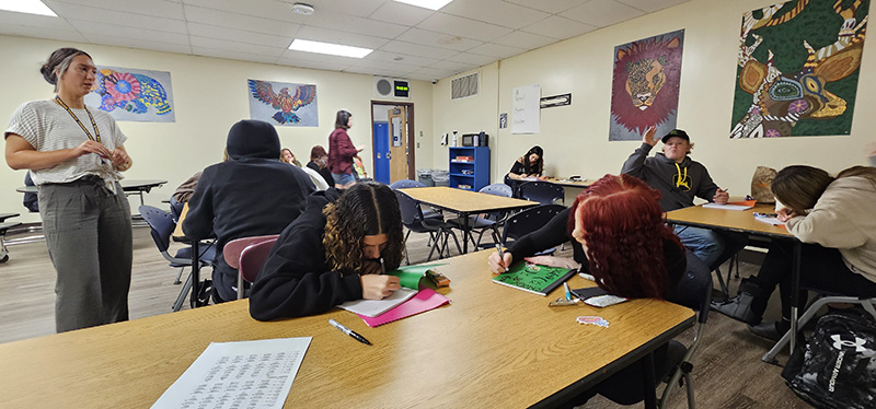 High school students sit at tables working 