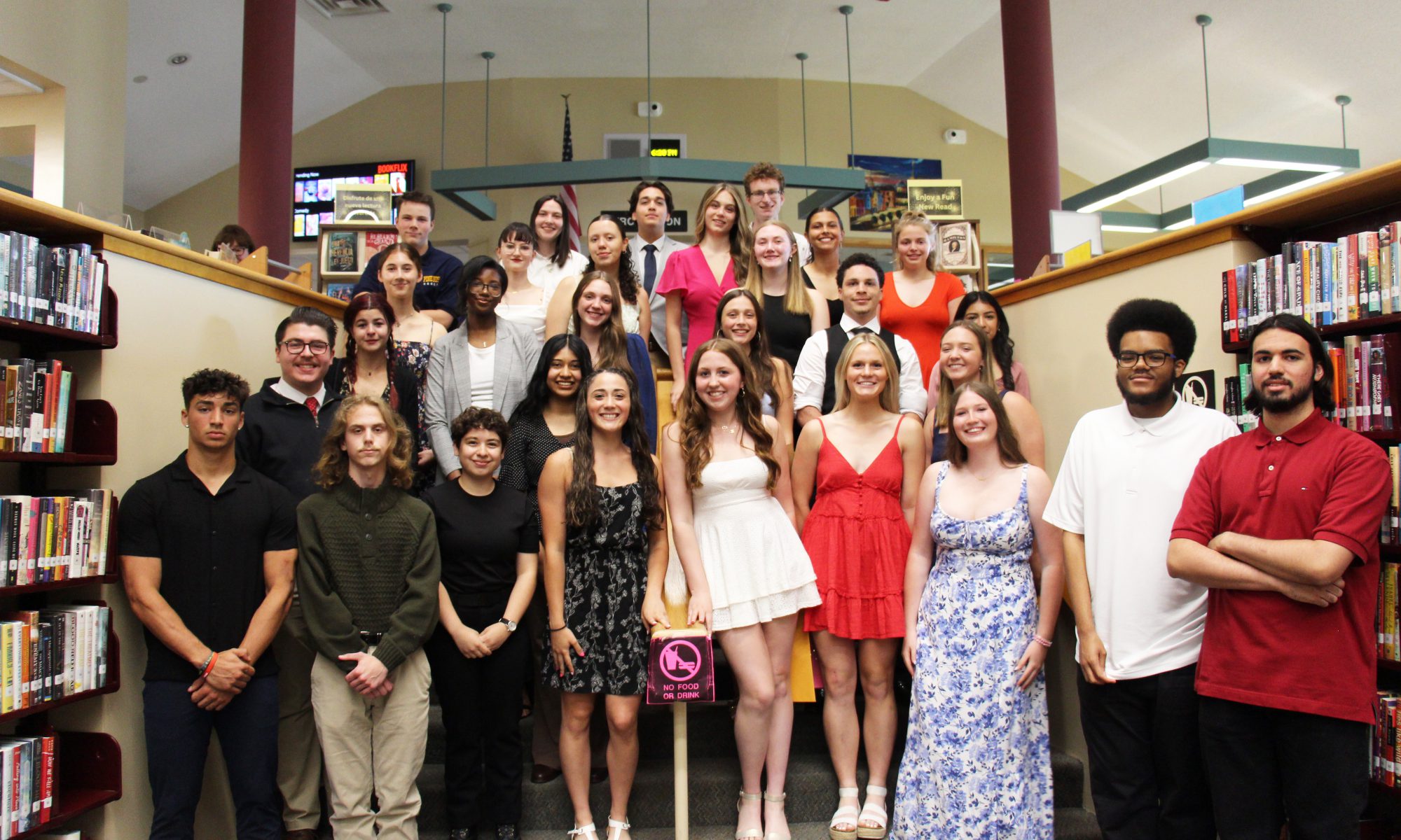 A group of 29 high school seniors stand in rows on steps. They are all smiling