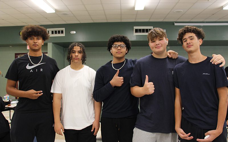 Five high school boys stand together, two with thumbs up.