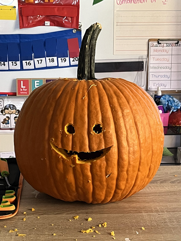 A pumpkin carved with eyes and a smile with one tooth.