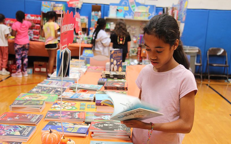 Three girls looking up at the camera smiling holding their new dictionaries