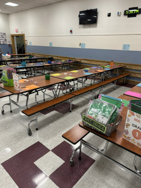 Tables in a cafeteria with learning materials on them.