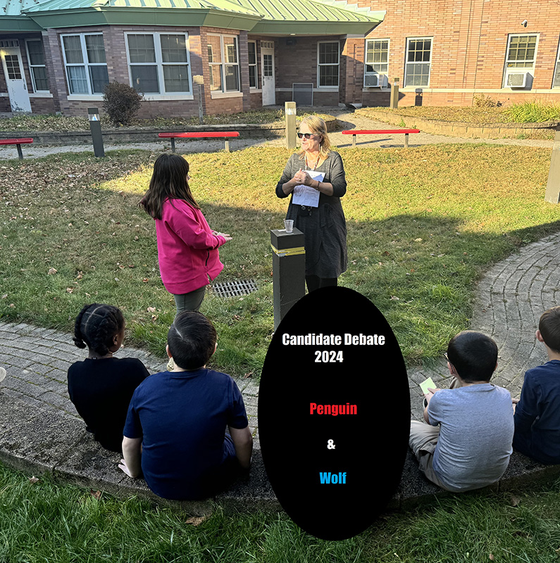 Students sit outside on grass and listen to someone talk about elections.