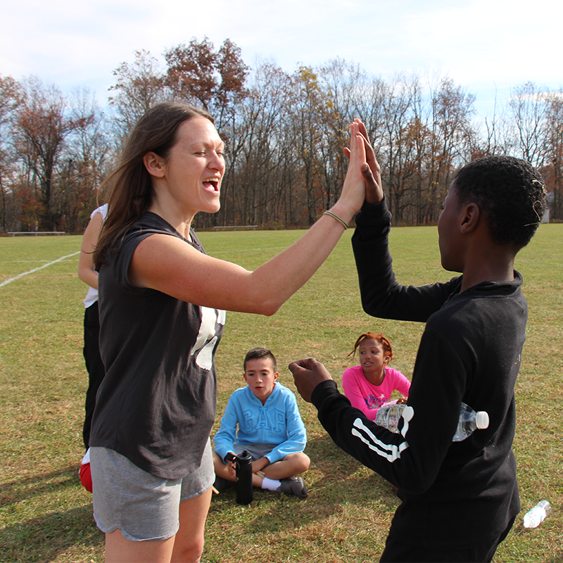 A woman high fives an elementary kid after he won a race.