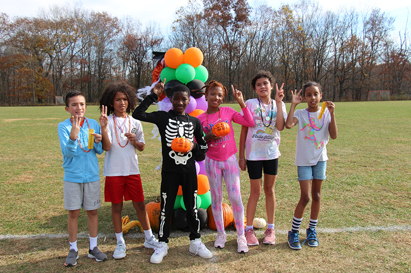 Six fifth-grade students - three boys and three girls wave.