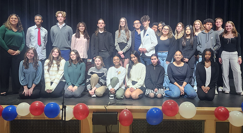 A large group of high school students, half sitting and half standing on a stage.