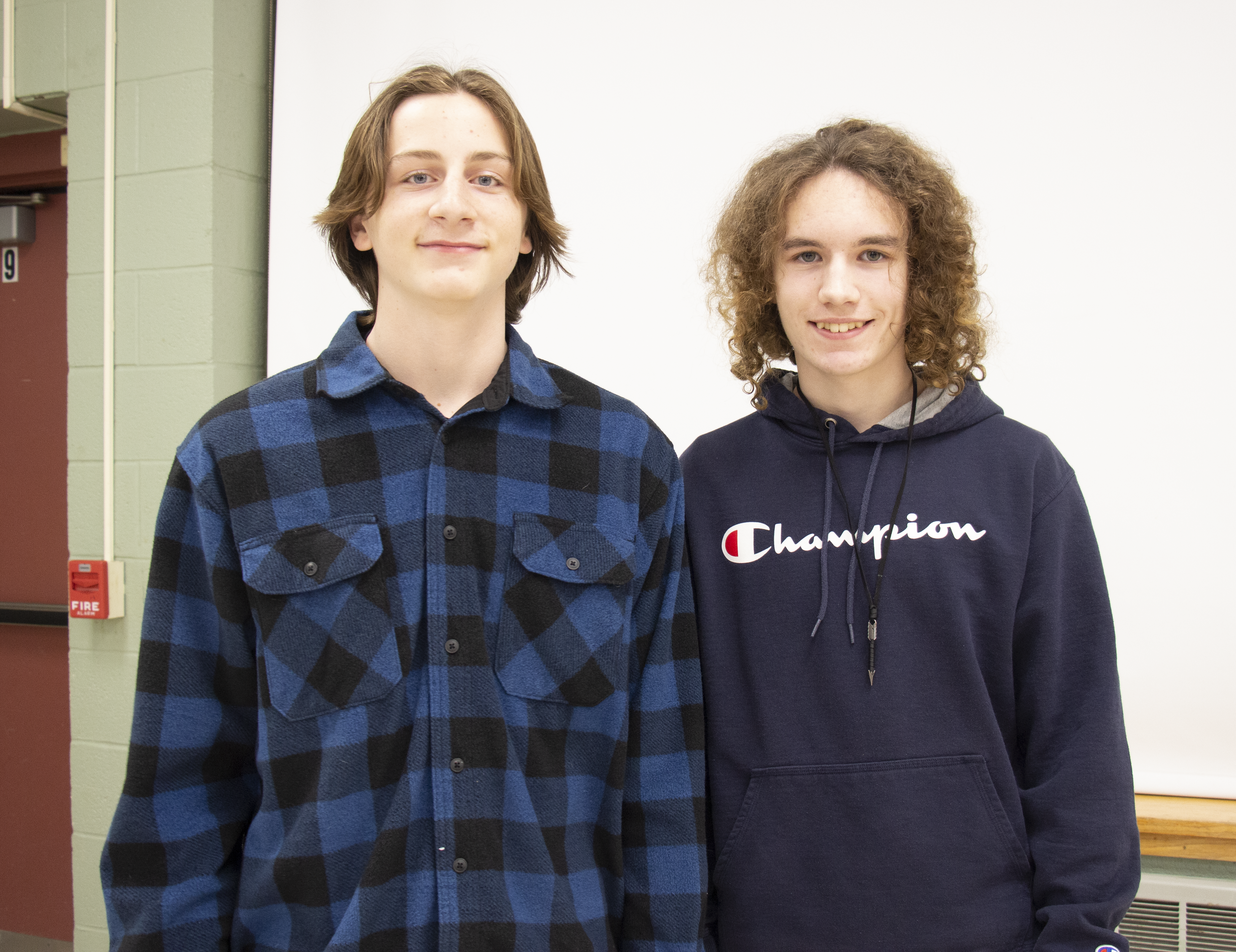 Two high school boys stand together and smile.