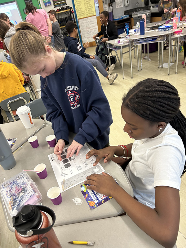 Two fifth=grade girls work together on an experiment.