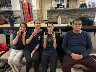 A group of four high school kids sit together giving thumbs up.