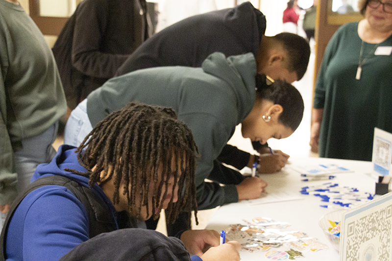 A group of high school kids sign papers.